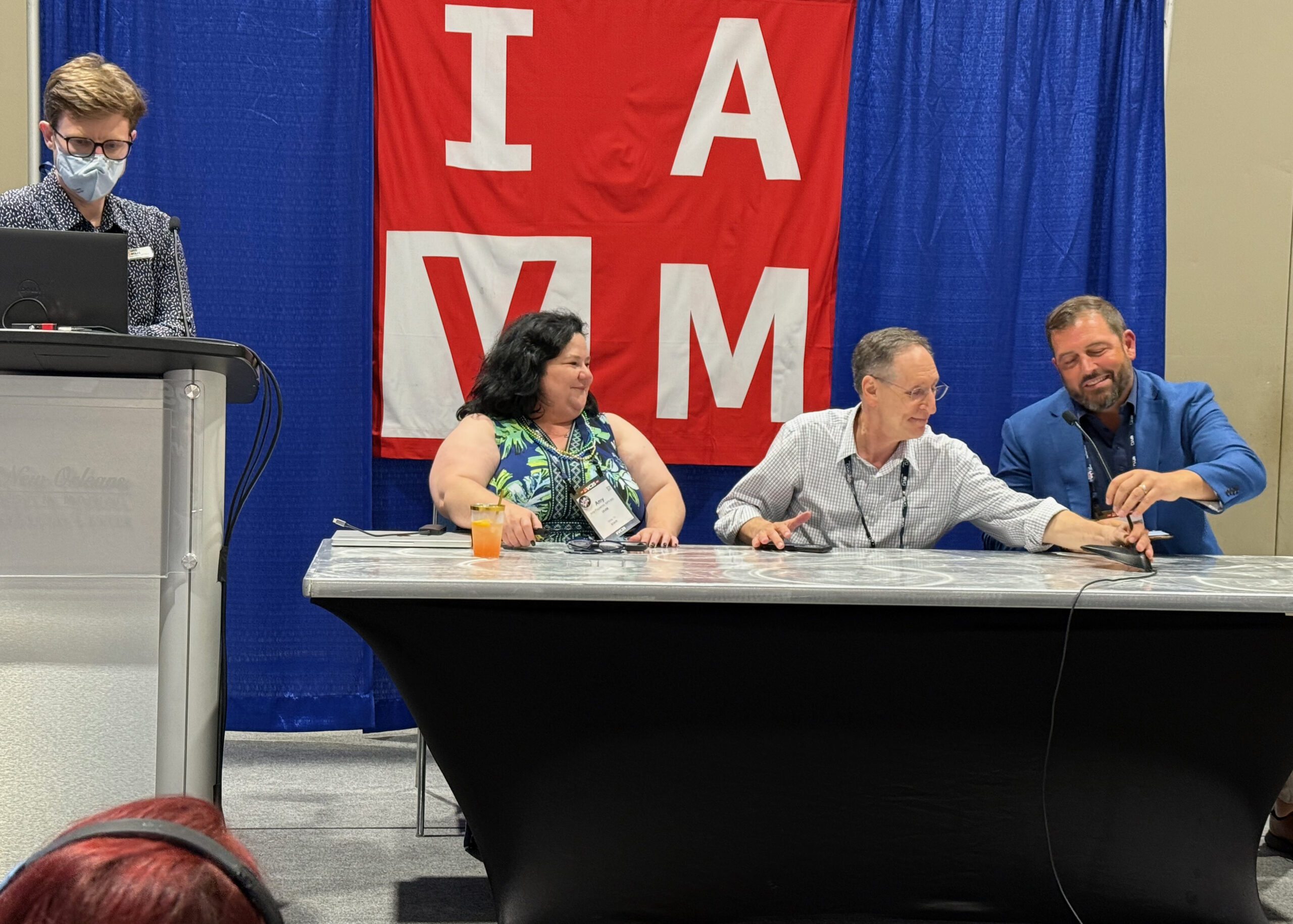 Amy Fitzpatrick, Bobby Goldwater, CVE, and Shane Beardsley introduce IAVM Online in the Innovation Theater at VC25. Greg Wolfe, IAVM Director of Education, is at the podium.