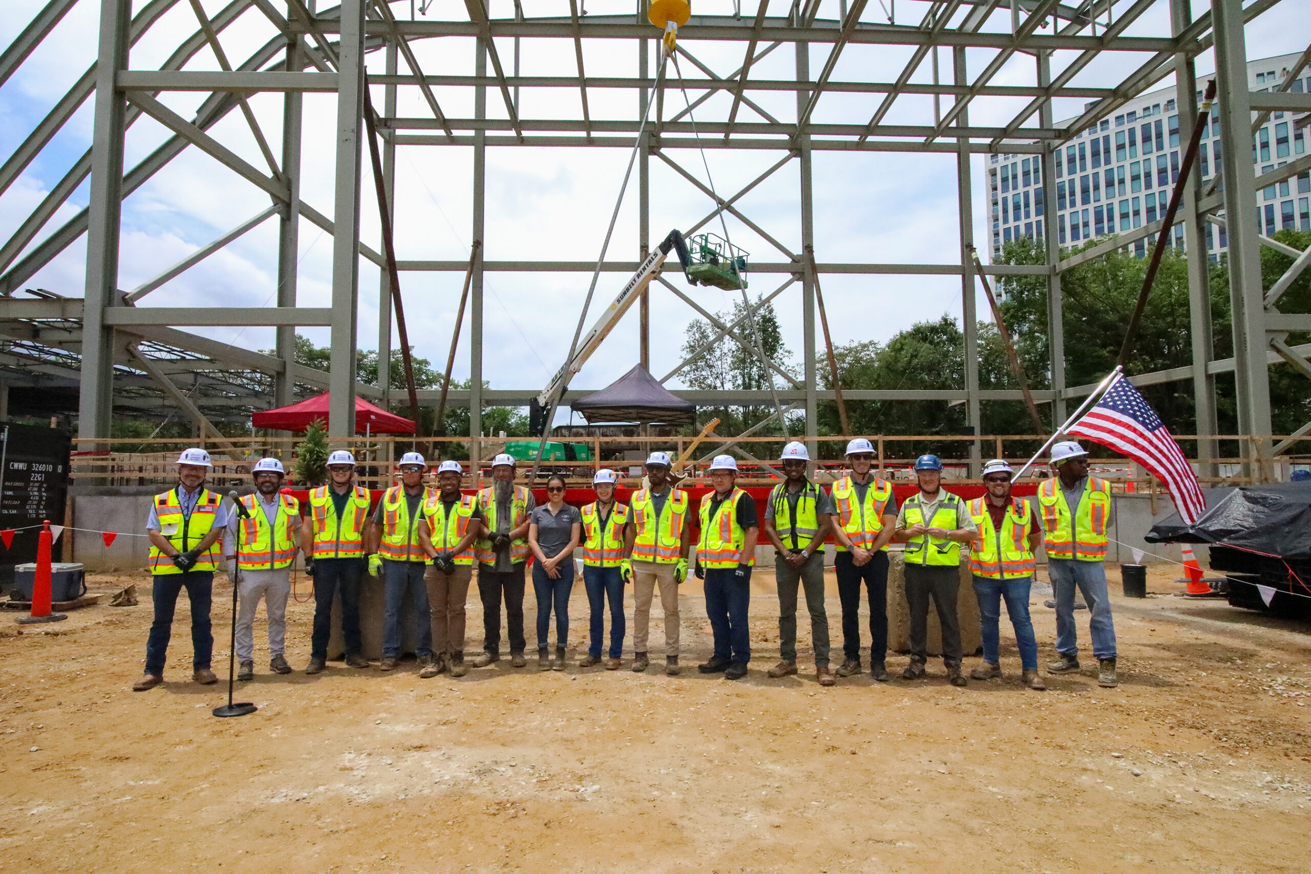 A group of people in high-visibility vests and hardhats pose in front of a building undergoing construction