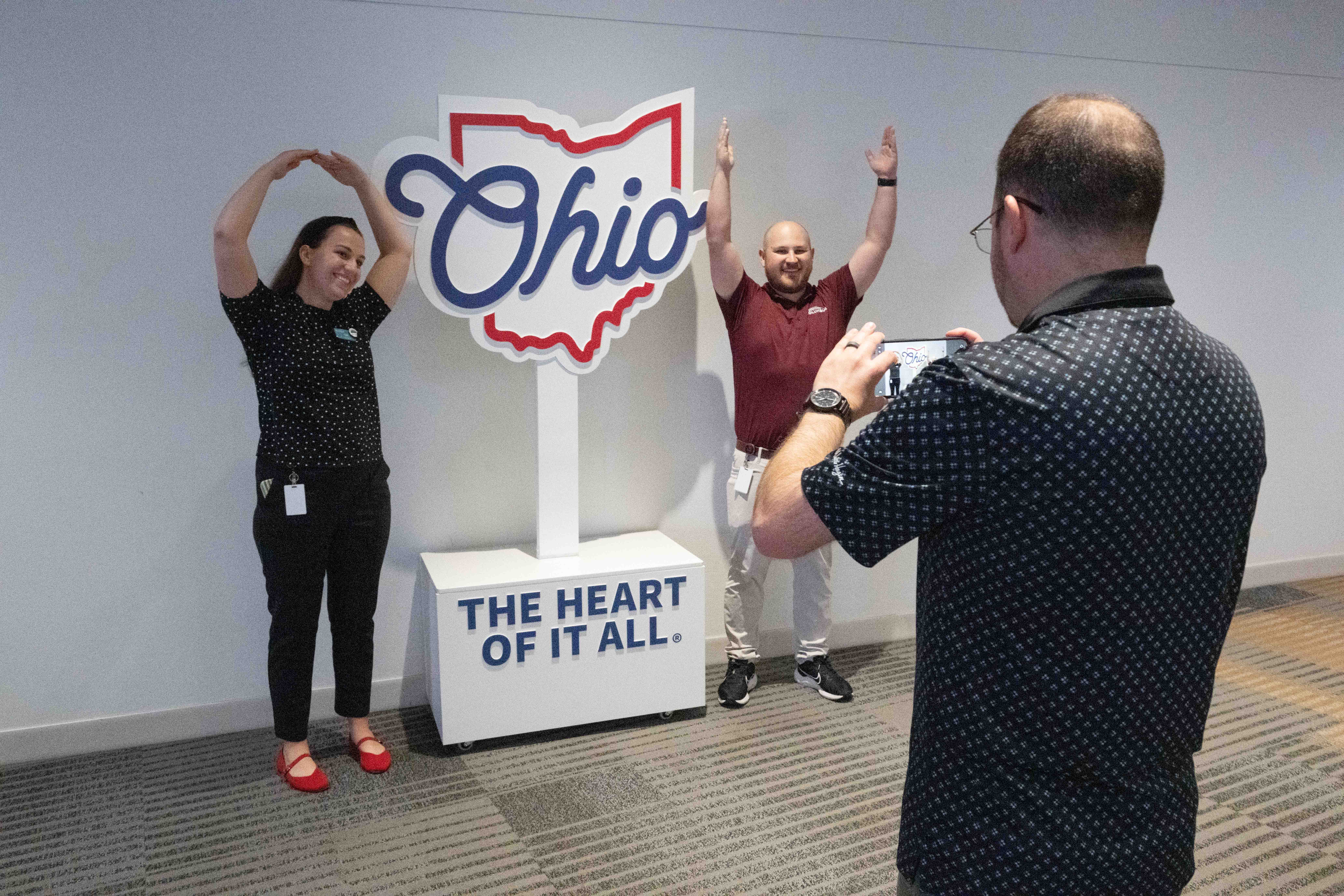 two people pose for a photo opportunity by a sign that says "Ohio. The heart of it all."